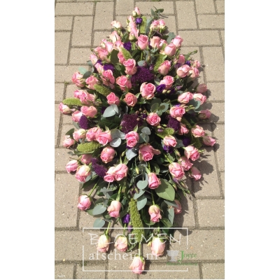 Roze rozen rouwarrangement in langwerpige vorm met blauw accent